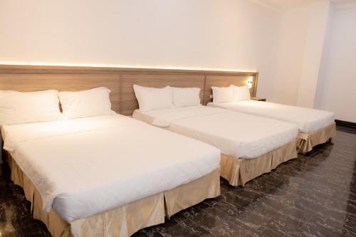 two beds in a hotel room with white sheets at Miền Tây Hotel in Can Tho
