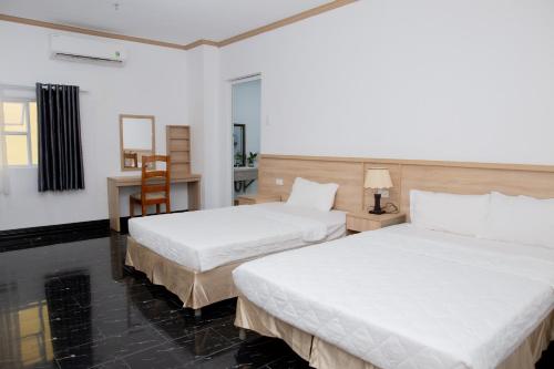 a hotel room with two beds and a desk at Miền Tây Hotel in Can Tho