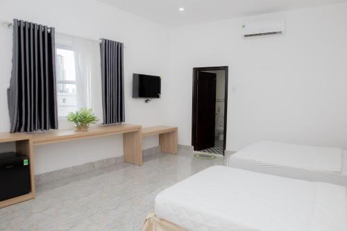 a bedroom with a bed and a tv and a window at Miền Tây Hotel in Can Tho