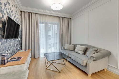 a living room with a couch and a glass table at GRANO APARTMENTS Gdańsk Old Town SPA & Wellness - GRANO APARTMENTS Gdańsk Residence SPA & Wellness in Gdańsk