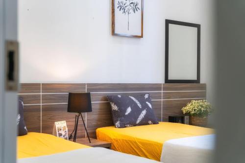 two beds in a room with yellow sheets and a mirror at La Cle' Đà Lạt in Da Lat