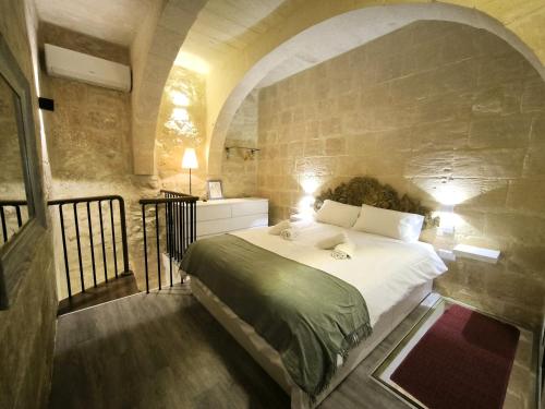 a bedroom with a large bed with a stone wall at Valletta St Ursula in Valletta