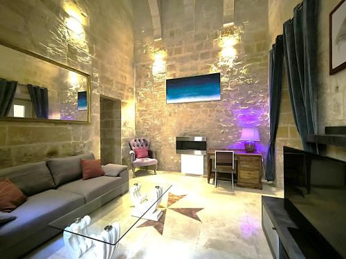 a living room with a couch and a stone wall at Valletta St Ursula in Valletta