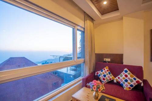 a living room with a red couch and a large window at Perfectstayz Value Valley Vista 5 min walk to Mall road in Mussoorie