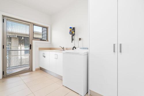 a white kitchen with a sink and a window at Mariner House in Port Fairy