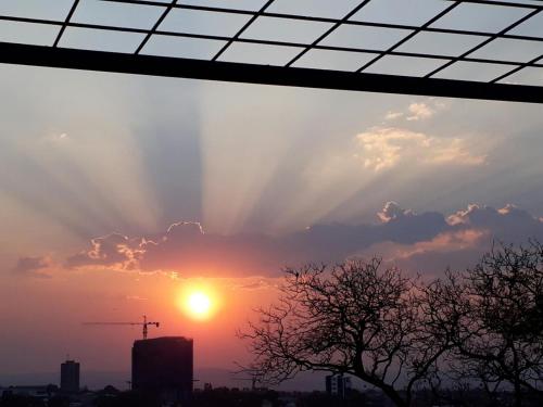 a sunset from a window with the sun in the sky at Villa Vista Guesthouse, Windhoek, Namibia in Windhoek