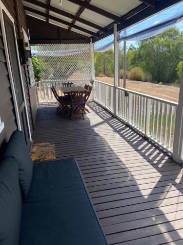 a porch with a table and a bench on it at Emu Cottage in Deeside