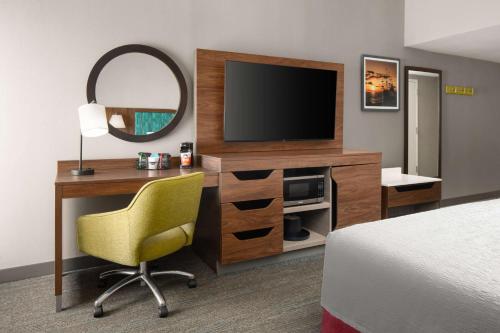 a hotel room with a desk with a television and a chair at Hampton Inn Sturbridge in Sturbridge