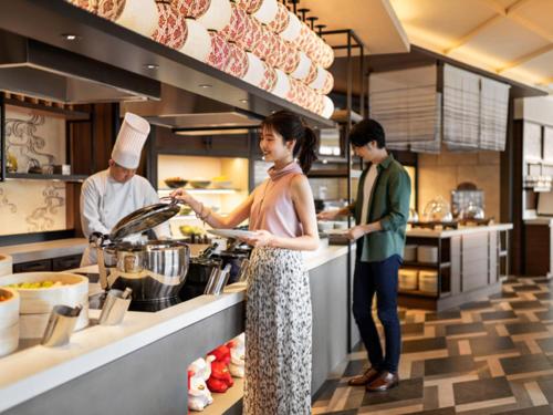 a woman standing in a kitchen preparing food at DoubleTree by Hilton Osaka Castle in Osaka