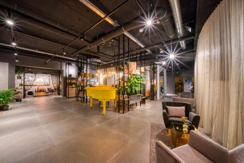 a lobby with a yellow table and some plants at Vienna House Easy by Wyndham Amsterdam Airport Schiphol in Hoofddorp