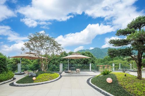 a patio with umbrellas and a garden with mountains at Z HOTEL- Qingchengshan in Dujiangyan