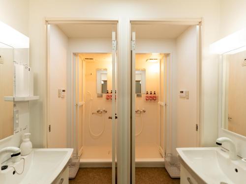 a white bathroom with a shower and two sinks at まち宿門 in Nakatsugawa
