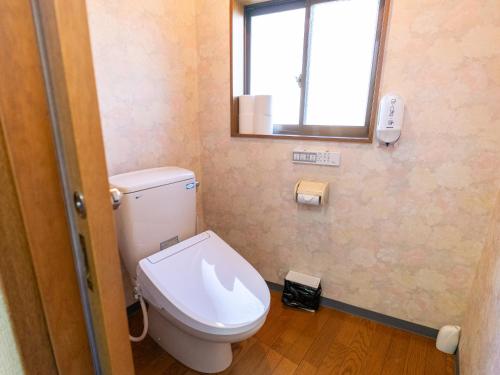 a bathroom with a toilet with a mirror and a window at まち宿門 in Nakatsugawa
