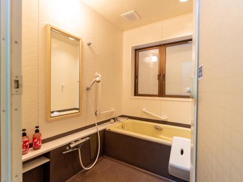 a bathroom with a bath tub and a mirror at まち宿門 in Nakatsugawa