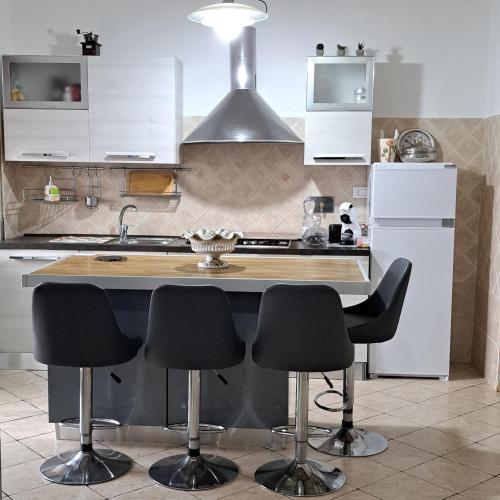 a kitchen with a kitchen island with black bar stools at La Casa di Ale 2 - ampio e luminoso appartamento ai Castelli Romani in Marino
