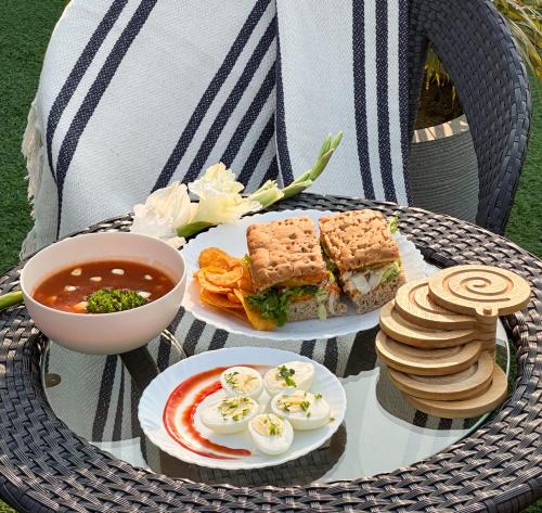 a table with two plates of sandwiches and a bowl of soup at Housr Sector 42 Gurgaon Golf Course Road Near 42-43 Metro Station in Gurgaon