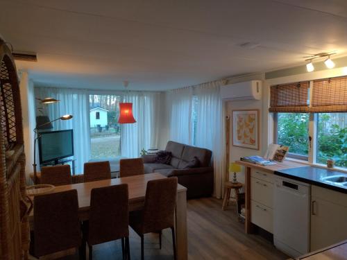 a kitchen and living room with a table and a couch at Wulft 47 Zonnig gezellig 6p chalet met zwembad in bosrijke omgeving op Familie Camping de Vossenburcht in IJhorst