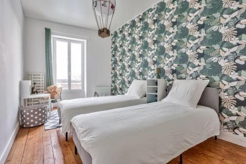 deux lits dans une chambre avec papier peint fleuri dans l'établissement Maison familiale au cœur du vignoble de St Emilion, à Montagne