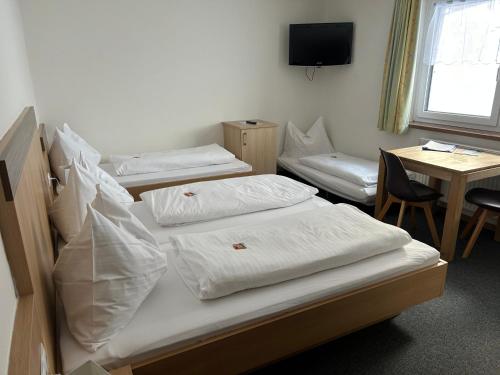 three beds in a room with a table and a television at Frühstückspension Auer - Haus Kargl in Schladming