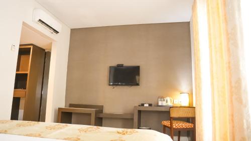 a hotel room with a bed and a tv on the wall at Tasneem Hotel Malioboro Yogyakarta in Yogyakarta