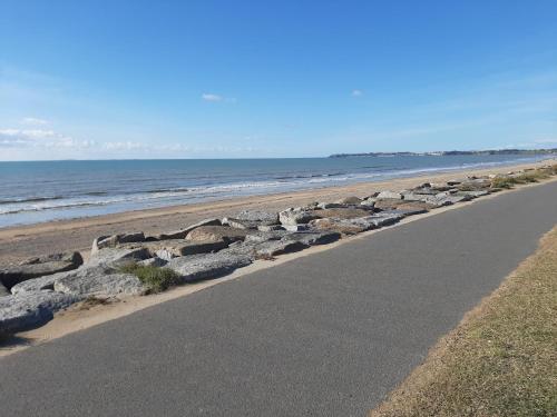 une route à côté d'une plage avec des rochers et l'océan dans l'établissement Appartement 2 pieces, à Jullouville