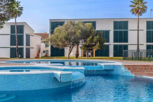 a pool with blue tiles in front of a building at Apartamento Cala´n Bosch Planta Bj in Cala'n Bosch