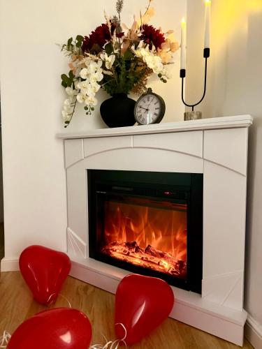 a fireplace with two red chairs and a clock at Resita Dream Apartament in Reşiţa