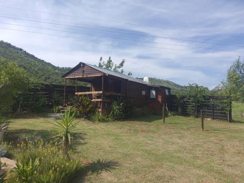 a wooden cabin in a field with a fence at Chalet 4 at Cynthias Country in Hartbeespoort