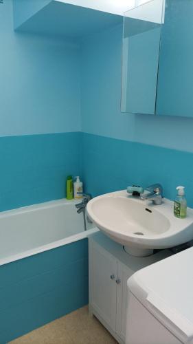 La salle de bains est pourvue d'un lavabo blanc et d'un mur bleu. dans l'établissement le cottage vue mer, à Benerville-sur-Mer