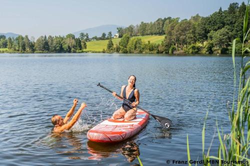 a woman and a man on a paddle board in a lake at Ferienparadies Hecher Maltschachersee in Feldkirchen in Kärnten