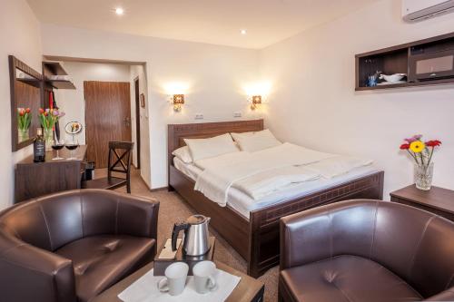 a hotel room with a bed and two chairs at Hotel Kolonie in Frýdlant nad Ostravicí