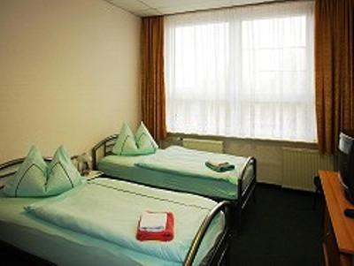 2 Einzelbetten in einem Zimmer mit Fenster in der Unterkunft Gaststätte & Pension Am Tanger in Prenzlau