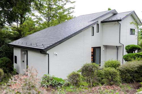 a white house with a black roof at 箱根温泉別邸白鷺 天然温泉 個室サウナ癒しの貸切宿 箱根の絶景と共に最大8名宿泊可 in Hakone
