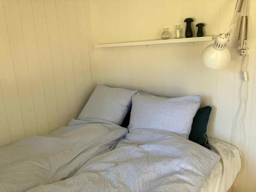 a bed with blue sheets and pillows in a room at Cozy Summer House Near Rågeleje in Vejby