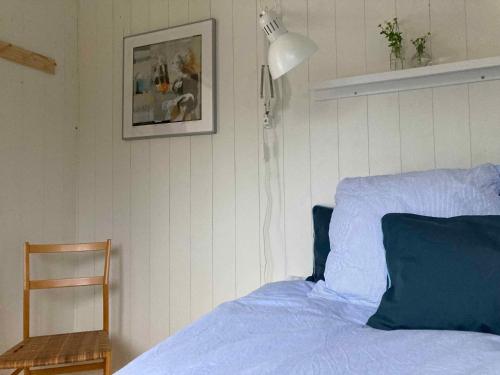 a bedroom with a bed with blue sheets and a lamp at Cozy Summer House Near Rågeleje in Vejby
