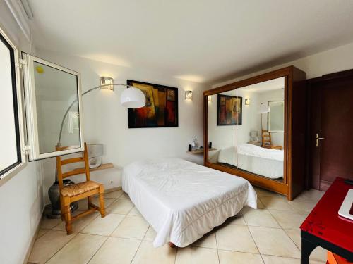 een slaapkamer met een wit bed en een spiegel bij Villa proche du centre-ville de Porto-vecchio et de ses plus belles plages in Porto-Vecchio