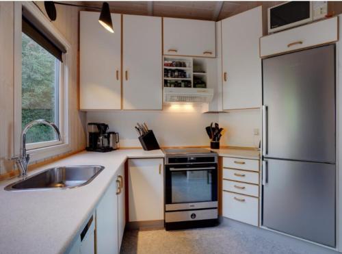a kitchen with white cabinets and a stainless steel refrigerator at Hidden Gem With A Great View in Broager