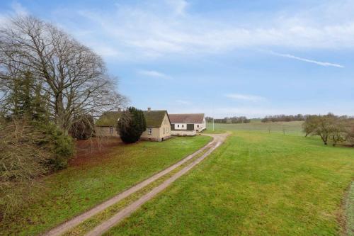 a house in a field next to a dirt road at Countryside Property With Great Fishing Options in Holbæk