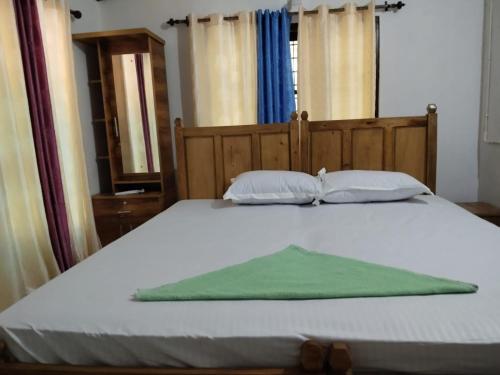 a bed with two pillows and a green blanket at Creekshore Home Stay in Kallar-Bridge