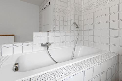 a white bath tub with a shower in a bathroom at Maison 9 personnes a Venthône, sauna et vue in Venthone