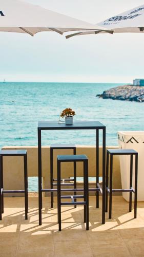 a black table and two chairs and the ocean at Mediterranea Hotel & Convention Center in Salerno