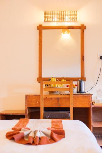 a bedroom with a bed with a desk and a mirror at Prakriti Resort and Organic Farm Pvt. Ltd. in Burhānilkantha