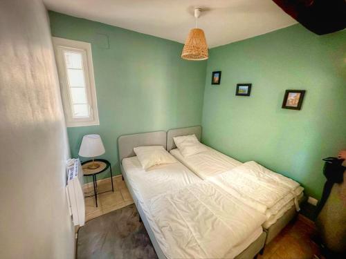 - une chambre avec un lit blanc dans un mur vert dans l'établissement Appart' au cœur du village, La Garde Freinet, à La Garde-Freinet
