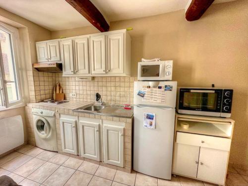 La cuisine est équipée d'un réfrigérateur blanc et d'un four micro-ondes. dans l'établissement Appart' au cœur du village, La Garde Freinet, à La Garde-Freinet