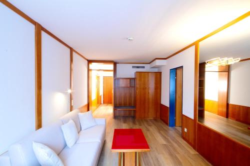 a living room with a white couch and a red table at Vienna Sporthotel in Vienna