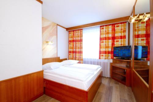 a small bedroom with a bed and a television at Vienna Sporthotel in Vienna