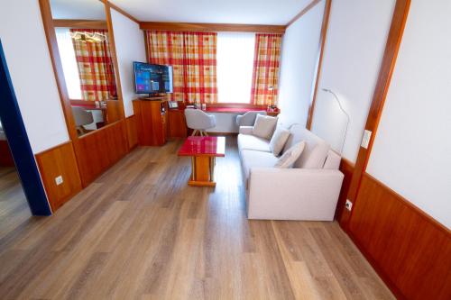 a living room with a white couch and a tv at Vienna Sporthotel in Vienna