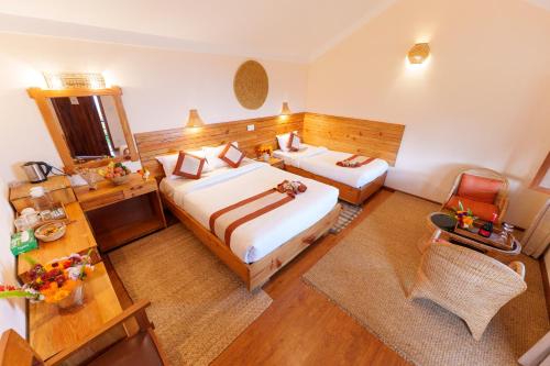 a hotel room with two beds and a table at Prakriti Resort and Organic Farm Pvt. Ltd. in Burhānilkantha