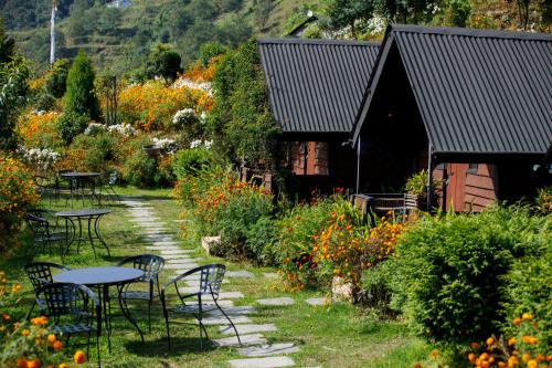 a garden with tables and chairs in front of a building at Prakriti Resort and Organic Farm Pvt. Ltd. in Burhānilkantha