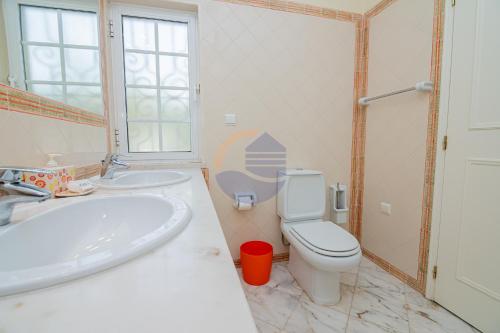 ein Badezimmer mit einer weißen Toilette und einem Waschbecken in der Unterkunft Villa Suites Outdoor pool with golf view in Portimão